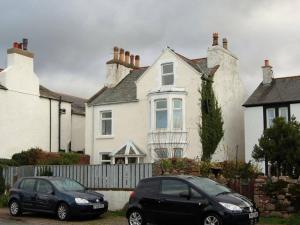two cars parked in front of a white house at Muncaster Cottages in Ravenglass