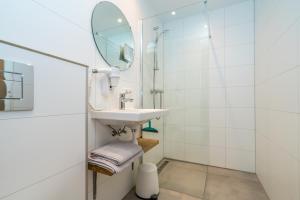 La salle de bains est pourvue d'un lavabo et d'un miroir. dans l'établissement De Herberg Appartementen, à Renesse