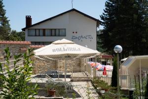 a white building with an umbrella in front of it at Hotel Velista in Voneshta Voda