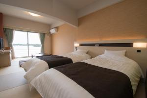a hotel room with two beds and a window at Hotel Listel Hamanako in Hamamatsu
