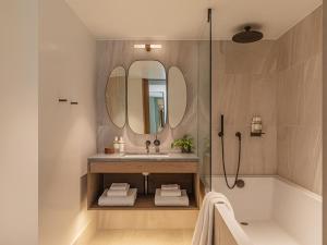 a bathroom with a sink and a tub and a mirror at The Stratford Hotel London in London