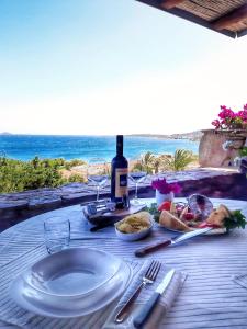 una mesa con un plato de comida y una botella de vino en Alma Del Mar Porto Rotondo en Porto Rotondo