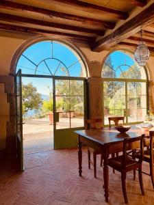 een eetkamer met een tafel en een aantal ramen bij La Fornella dell'Anita in Pelago