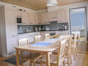 KukkolaにあるHoliday Home Suvela by Interhomeの白いキャビネット、テーブルと椅子付きのキッチンが備わります。