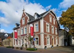 ein großes Backsteingebäude mit roten Bannern davor in der Unterkunft Hotel Tenbrock - Restaurant 1905 in Gescher