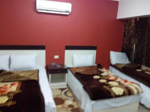two beds in a room with a red wall at Isis Hostel 2 in Cairo