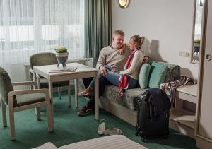 a man and woman sitting on a couch in a hotel room at Hotel Goethehof in Bad Gastein