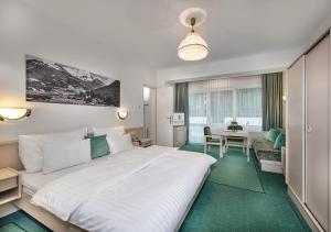 a bedroom with a large white bed and a table at Hotel Goethehof in Bad Gastein