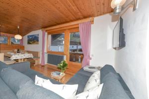 a living room with a blue couch and a television at Appartamenti Chedul in Selva di Val Gardena