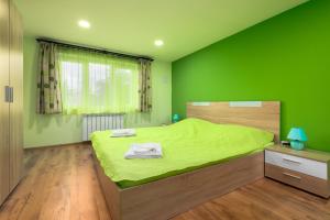 Serdika Round Tower Apartments في صوفيا: غرفة نوم خضراء مع سرير بملاءات خضراء