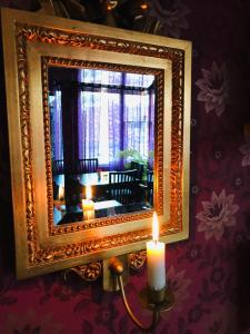 um espelho numa parede com uma vela à frente. em Vejbystrands Vandrarhem em Vejbystrand