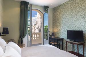 a bedroom with a bed and a tv and a window at Hotel Le Grimaldi by Happyculture in Nice
