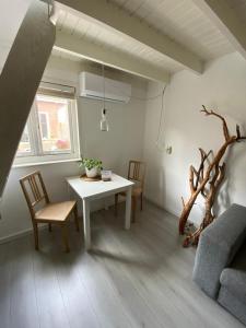 uma sala de estar com uma mesa branca e cadeiras em Zoute Zeelucht em Katwijk aan Zee