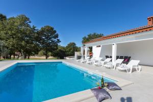 een zwembad met stoelen en een huis bij Villa Piljan in Bokordići