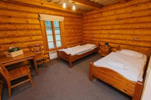 - une chambre avec 2 lits et un bureau dans une cabane en rondins dans l'établissement Atpūtas parks Lācītes, à Gulbene