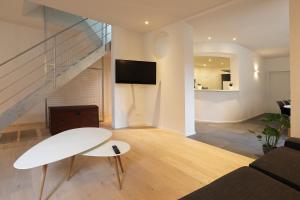ein Wohnzimmer mit einem weißen Tisch und einer Treppe in der Unterkunft Loft vakantiehuis in Veurne