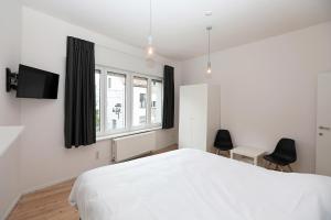 een slaapkamer met een wit bed en een raam bij Loft vakantiehuis in Veurne