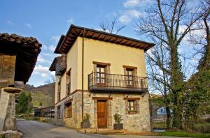 an old stone house with a balcony on a street at La Indiana in Poo de Cabrales