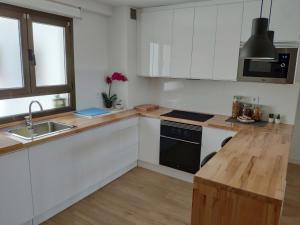 cocina con armarios blancos y encimera de madera en Apartamento LOS VEGA- parking privado, en Oviedo