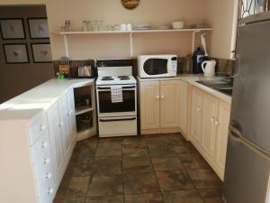 a kitchen with white cabinets and a stove and a microwave at Umsinsi Cottage in Hluhluwe