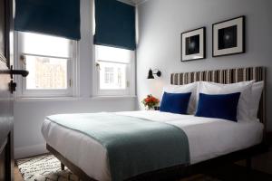 a bedroom with a large bed with blue and white pillows at The Coach in London