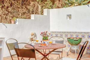 una mesa con sillas y un plato de comida en el patio en Private Heated Pool, Jacuzzi & 1225m2 garden in Villa Cipreses, en Frigiliana