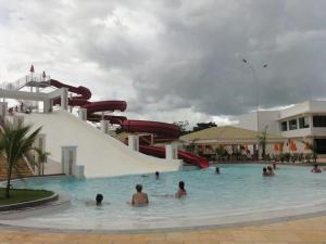 a group of people in a swimming pool with a water slide at Apartamento Lacqua Di Roma in Caldas Novas