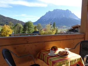 a table with a plate of food and a mountain at Apart Ideal in Lermoos