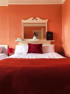 a red bedroom with a large bed with a red blanket at Caspian Hotel in London