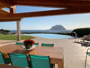 a wooden table with green chairs and a pool at VillaLuxx in Porto San Paolo