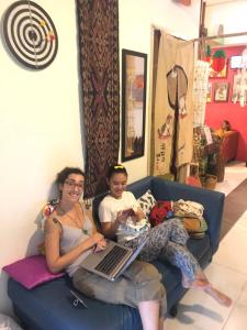 a woman and a child sitting on a couch with a laptop at Woodpecker Lodge, Kuching in Kuching