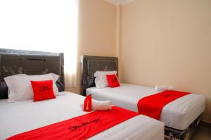 パルにあるRedDoorz near Millenium Waterpark Paluの赤い枕付きのベッド2台が備わる客室です。