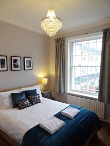 a bedroom with a bed with a chandelier and a window at Waterloo Pad - gorgeous one bed maisonette in Brighton & Hove