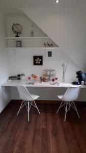a white counter with two white chairs in a room at B & B De Gouwe Plek in Hoogwoud