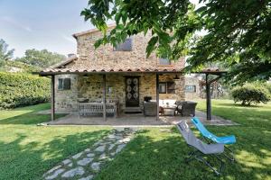 a stone house with a patio and chairs in the yard at Henry House in Cinigiano