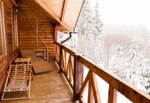 un balcone di una baita di tronchi con alberi innevati di Dachna Sadyba PB a Myhove