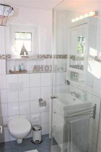 Baño blanco con aseo y lavamanos en Ferienvermietung Meerlandliebe, en Beschendorf