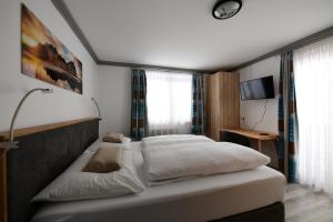 een slaapkamer met een groot bed met witte lakens bij Appartement Lechthaler in Embach