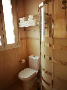 a bathroom with a toilet and a window and towels at La Casa Azul B&B + Apartments in Málaga