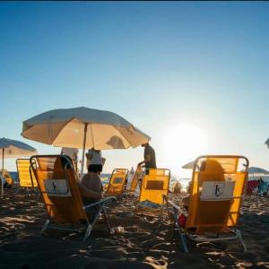 un gruppo di sedie e un ombrellone su una spiaggia di 6 personas FRENTE AL MAR- Complejo LINCOLN CENTER- Torre WASHINGTON a Punta del Este