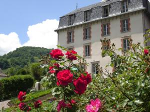 a building with red roses in front of it at La Maison de Jeanne, maison d'hôtes in Thiézac