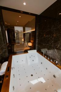 a bathroom with a bath tub with a large mirror at Privilege Hotel & Spa in Tirana