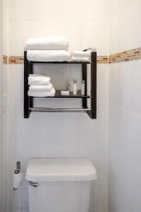 a bathroom with a toilet and a shelf with towels at Midtown West Hotel in New York