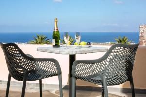 a table with a bottle of wine and two chairs at Anemoessa Villa in Oia
