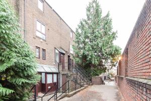 un callejón entre dos edificios de ladrillo con un árbol en White City Apartment en Londres