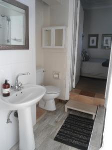 uma casa de banho com um lavatório branco e um WC. em "La Couronne" em Joanesburgo