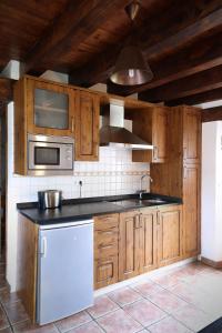 a kitchen with wooden cabinets and a sink and a microwave at Hotel Rural La Puebla in Orbaneja del Castillo