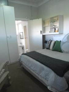 - une chambre avec un grand lit et une armoire blanche dans l'établissement "La Couronne", à Johannesbourg
