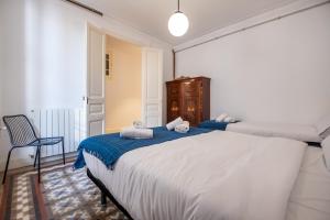 a bedroom with two beds and a chair at b42 - MODERNIST APARTMENT FOR LARGE GROUPS IN EIXAMPLE in Barcelona