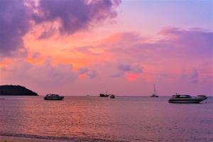 a group of boats in the water at sunset at Secret Garden Beach Resort in Bangrak Beach